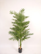 An indoor artificial palm plant in a black plastic pot, photographed against a plain white background.
